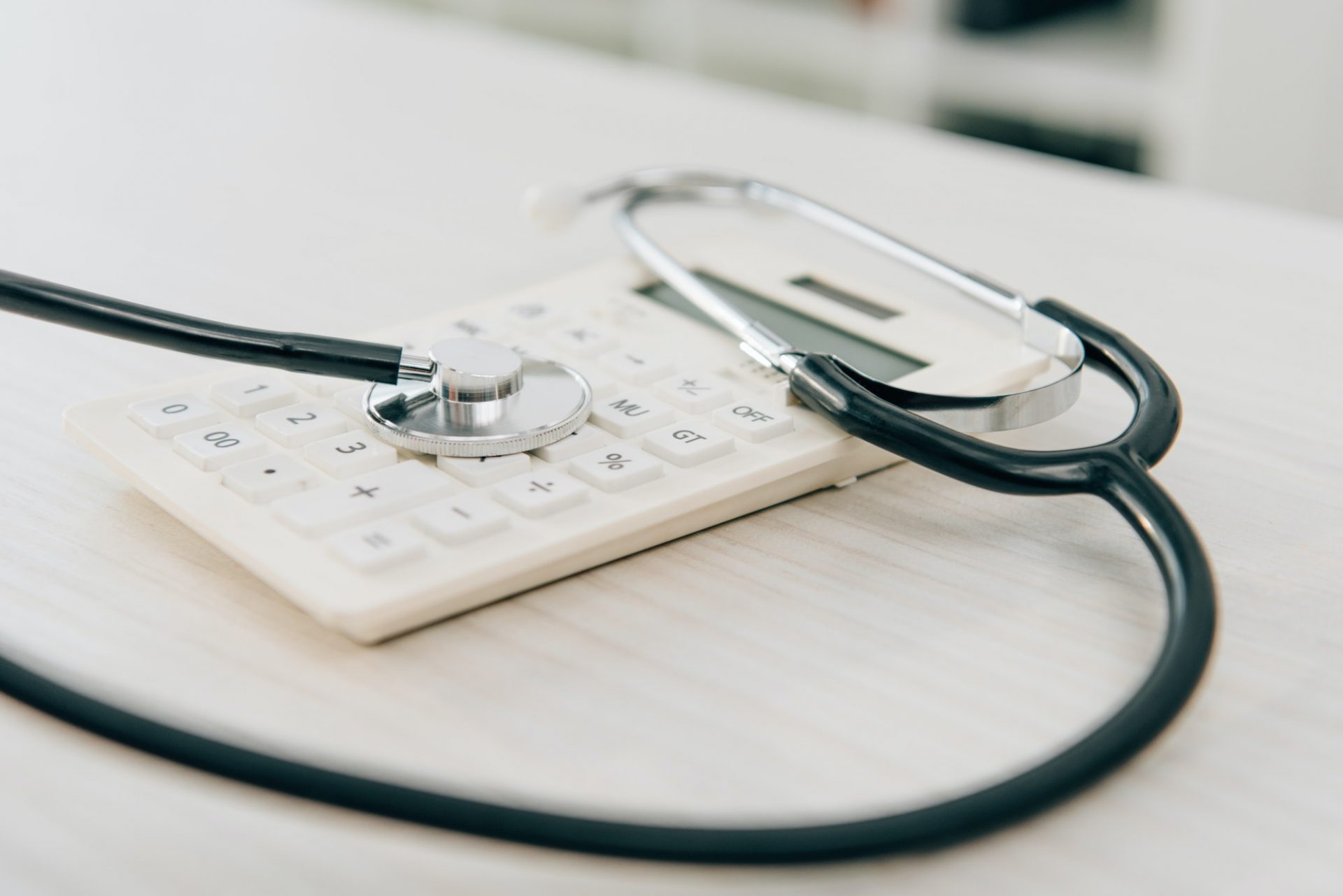 close up of stethoscope lying on calculator, health insurance concept