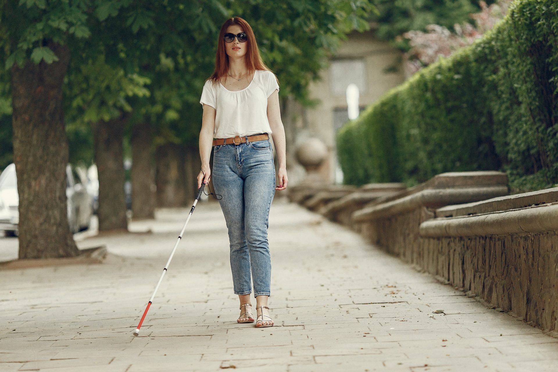 Young blind person with long cane walking in a city